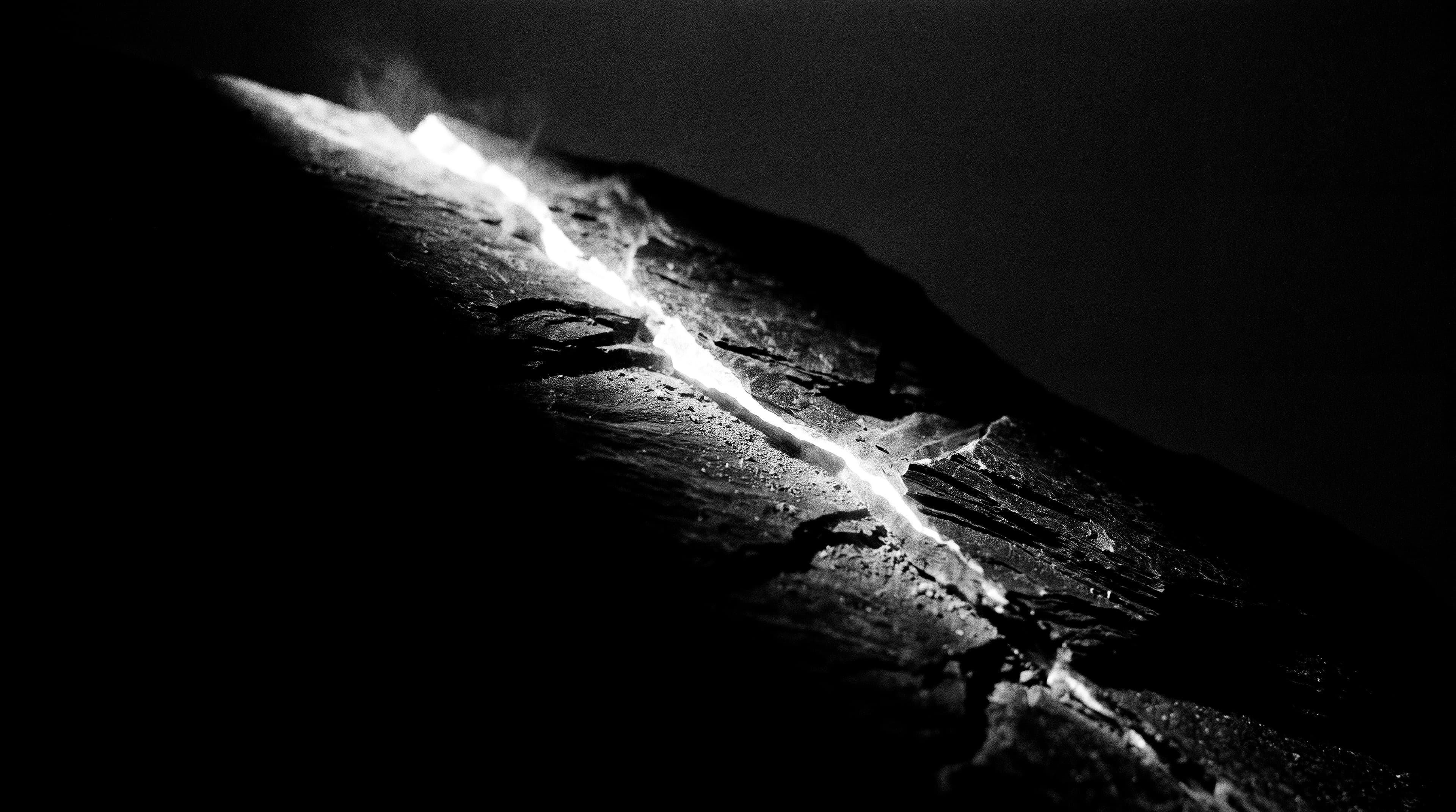 Dark mineral ridge split diagonally by a seam of light.