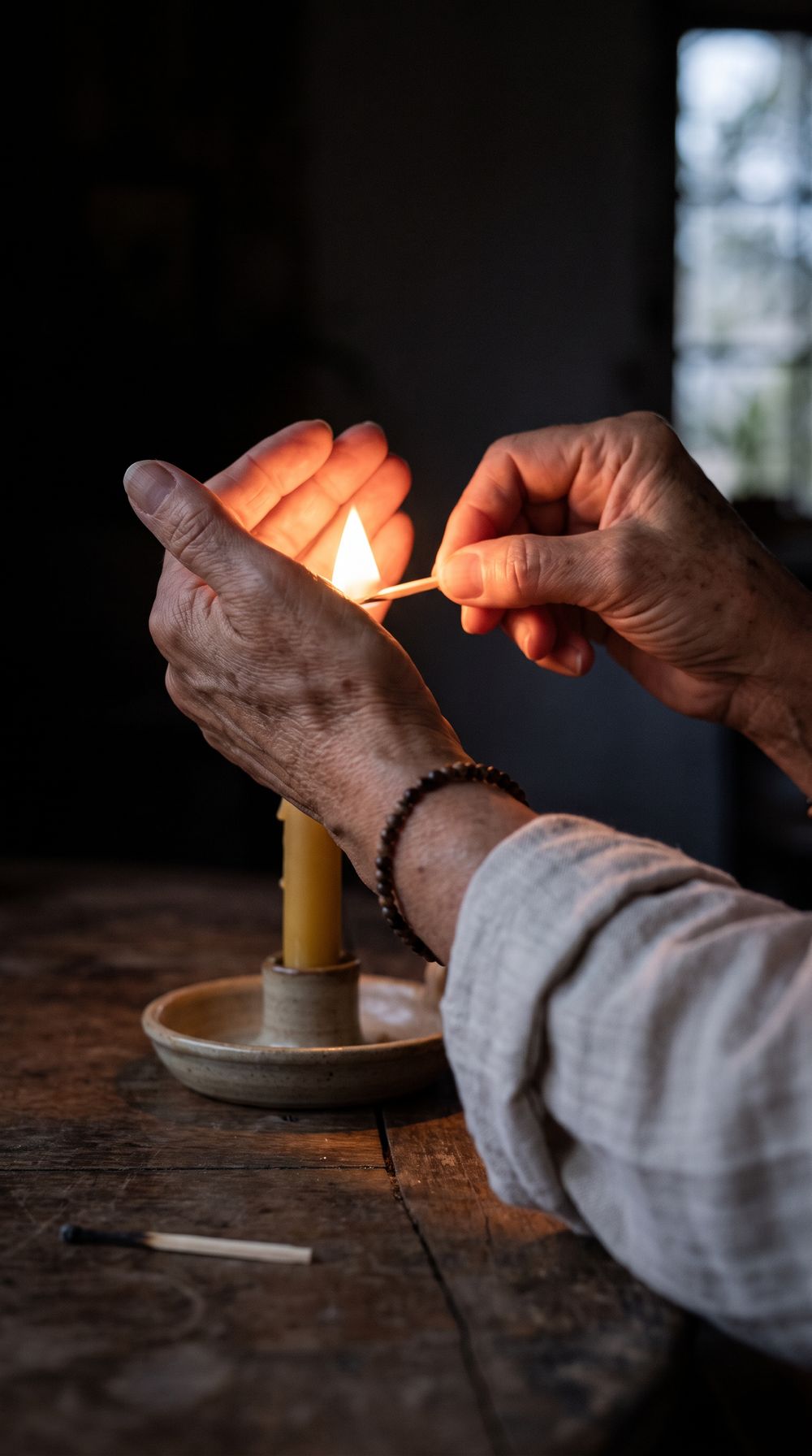 Hands light a candle at night.
